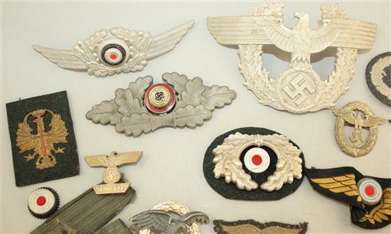 A collection of various German Third Reich cap badges, cloth badges and pins